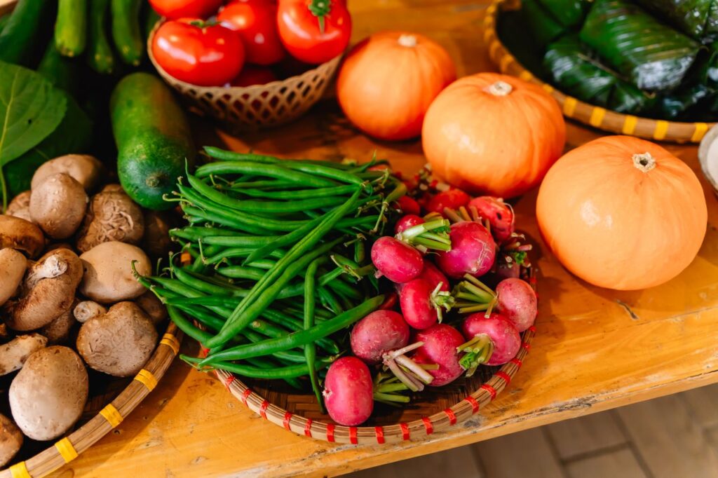 A vibrant display of fresh vegetables including tomatoes, pumpkins, and green beans on a wooden table.