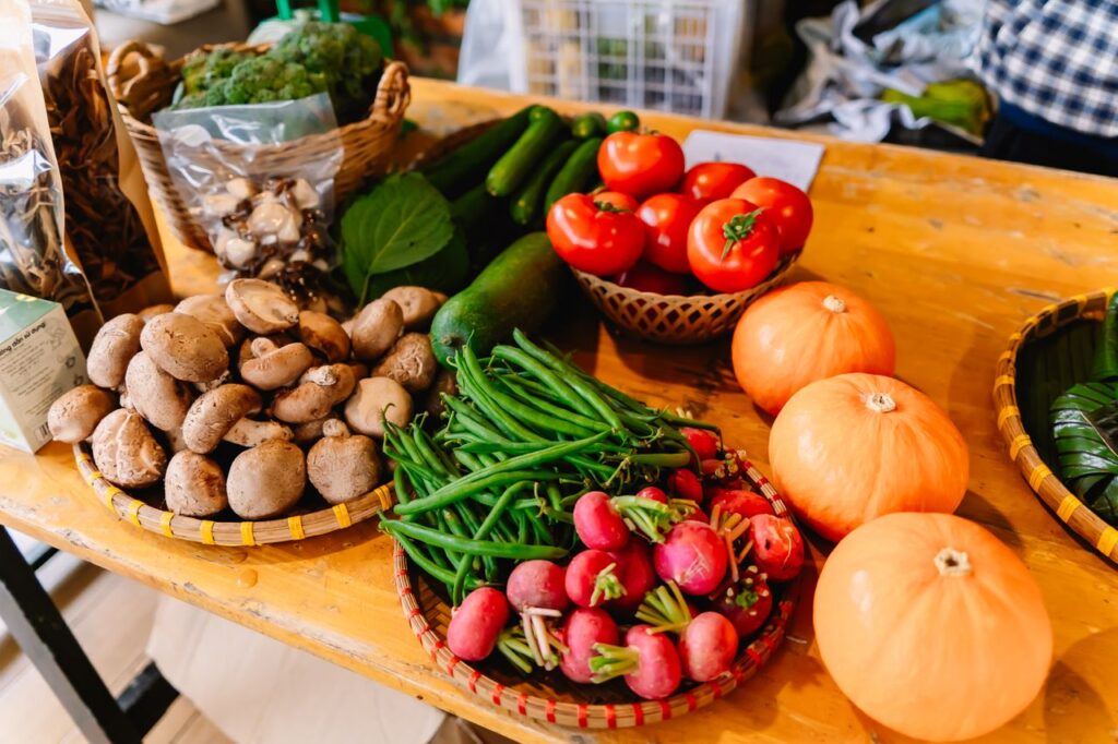 Vibrant display of fresh vegetables including mushrooms, tomatoes, pumpkins, and radishes on a market table.